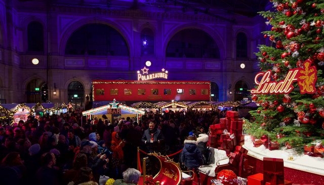 Besuchende am Markt, rechts der Lindt-Weihnachtsbaum, im Hintergrund der Polarzauber-Wagen.