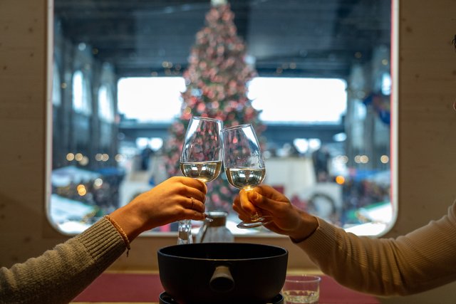 Anstossen im Fondue-Express, im Fenster der Weihnachtsbaum.