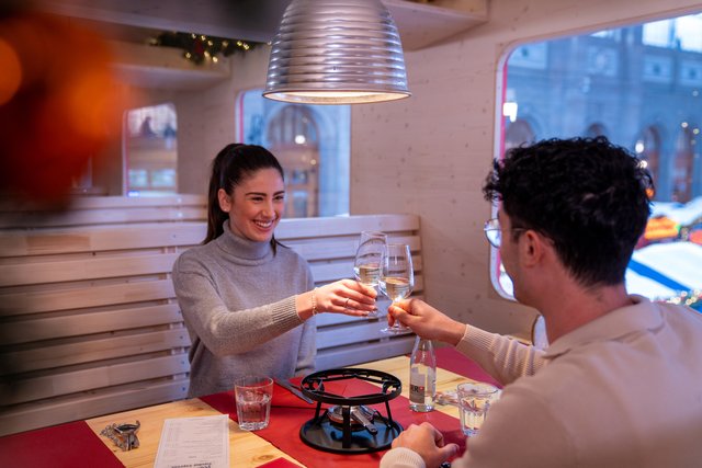 Zwei Gäste stossen im Parsennbahn Fondue-Express an.