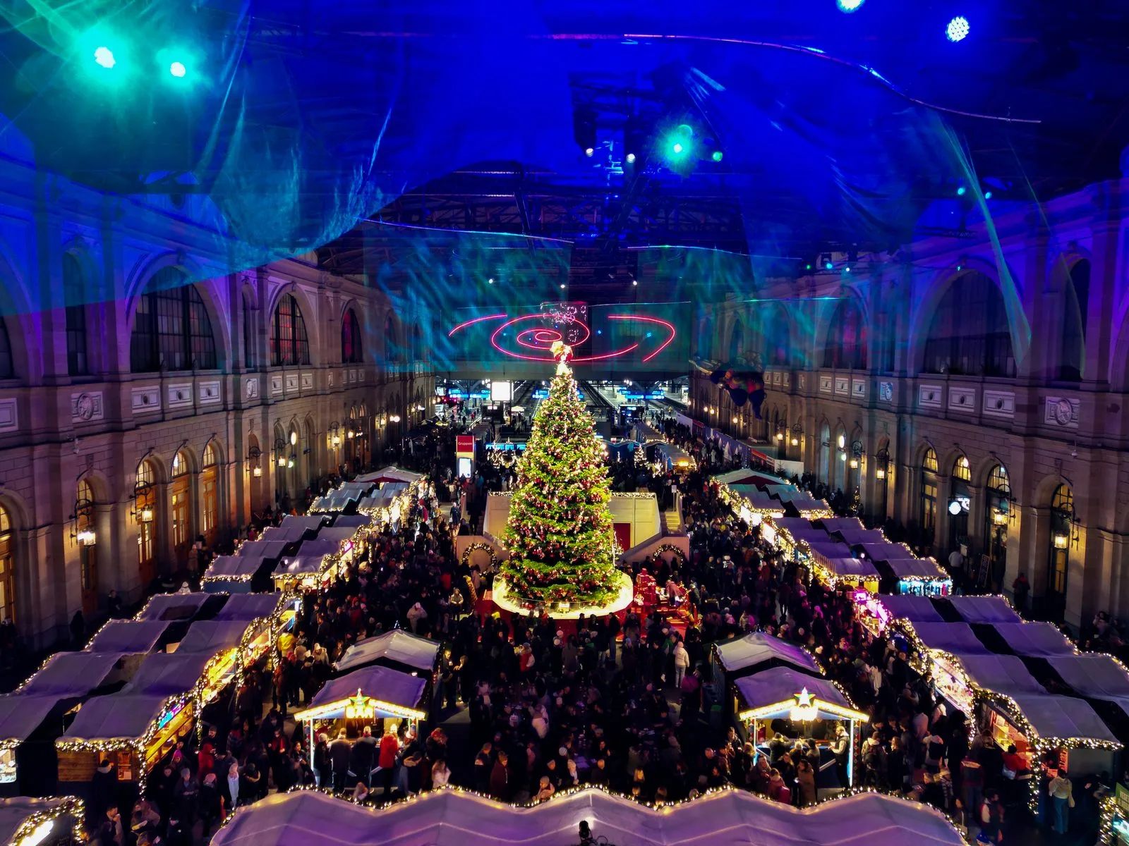 Le marché de Noël de la gare centrale de Zurich vu du ciel: des rangées de chalets et un sapin de Noël au milieu du hall
